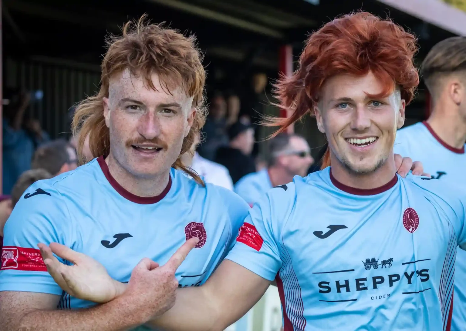 Taunton Town FC fans sport ginger mullet wigs in support of captain Tom Smith, sparking a booming trend at matches. The quirky craze has taken the club's home games by storm!