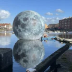 Luke Jerram's 30ft inflatable moon deflates twice due to storm damage in Somerset, cutting short the popular outdoor installation that had attracted over 10,000 visitors.