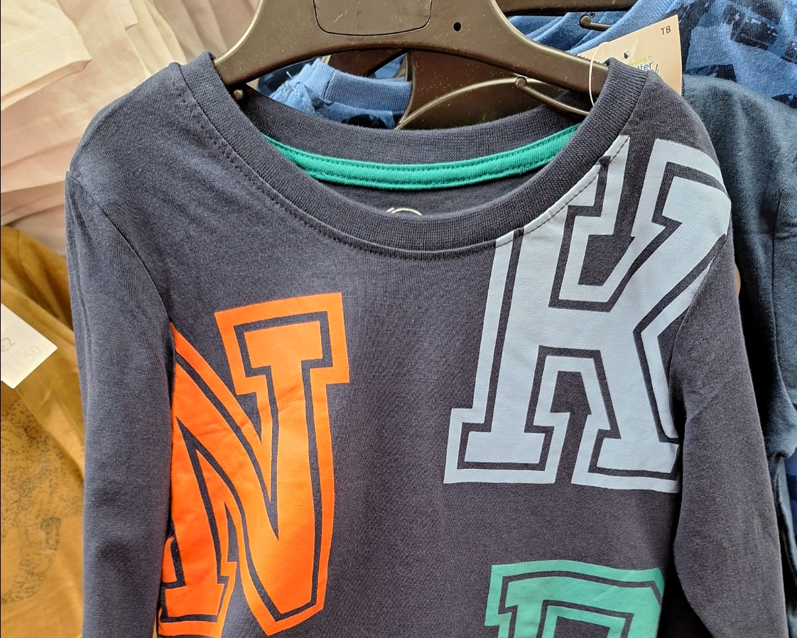 Mum Lucy spots unexpected message on kid's jumper, leaving shoppers amused as hidden word 'knob' sparks laughter and online reactions.