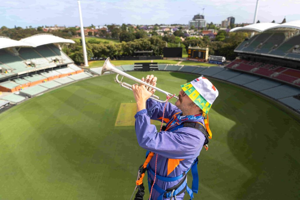 Barmy Army trumpeter Simon Finch sparks Ashes excitement atop Sydney Harbour Bridge, marking one year until England vs Australia 2025 series. Plan your trip now!