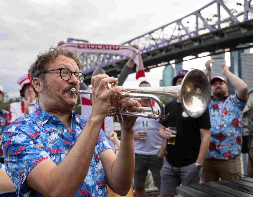 Barmy Army trumpeter Simon Finch sparks Ashes excitement atop Sydney Harbour Bridge, marking one year until England vs Australia 2025 series. Plan your trip now!