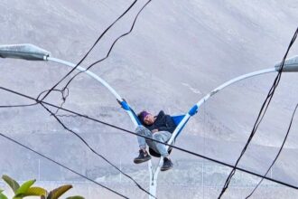 Bizarre rescue in Chile: A man found napping atop a lamp post in Iquique is safely brought down by firefighters, leaving stunned locals and traffic in disbelief.