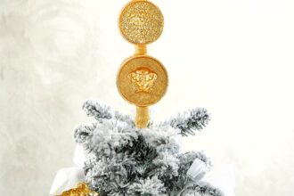 Versace is selling luxury Christmas tree toppers for up to £495, featuring Medusa and coin designs in glittery gold glass, sparking buzz over the festive splurge trend.