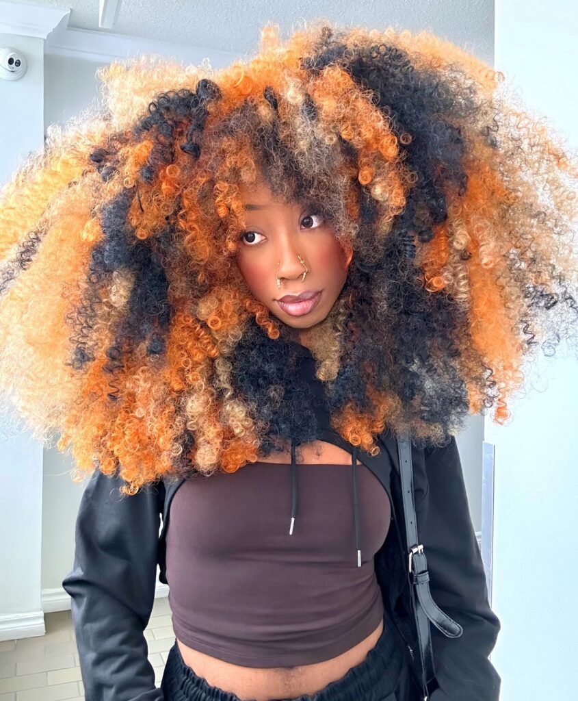 Fashion influencer Maryaam Lewis-Herbert stuns with festive candy cane-inspired hair for Christmas, blending red, white, and dark hues. Viral look garners 450K views!