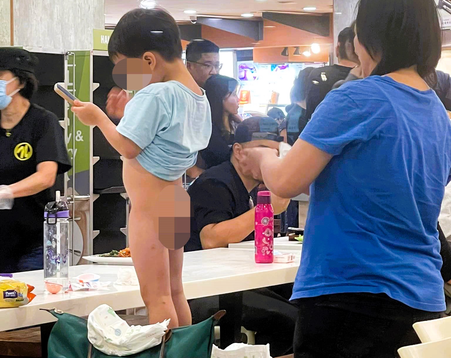 Diners were shocked as a mum changed her toddler's dirty nappy on a dining bench at a busy Singapore restaurant, sparking complaints about hygiene and public etiquette.