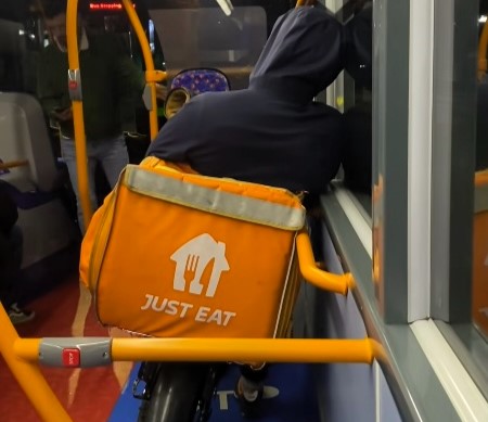 A Just Eat rider was spotted on a late-night London bus with his e-bike, sparking mixed reactions from passengers and locals over TfL's ban on non-foldable bikes.