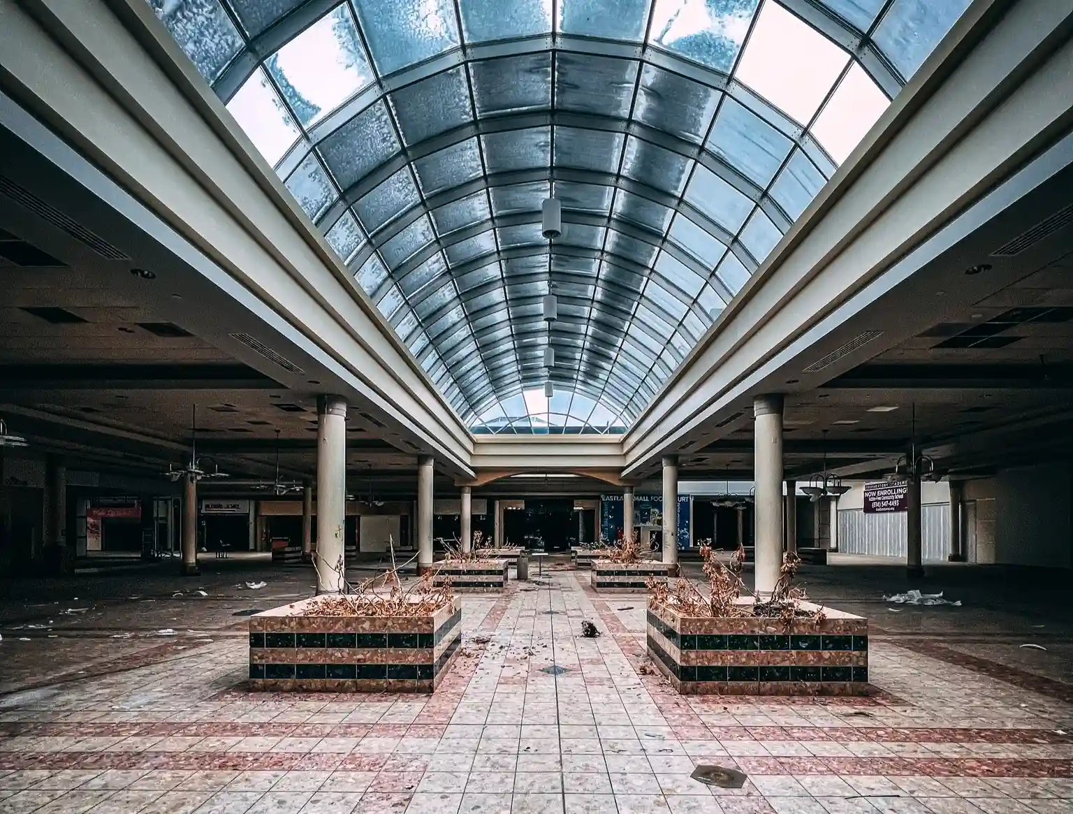 Explore the eerie remains of an abandoned Ohio mall, frozen in time with flooded floors, graffiti, and retro posters, sparking comparisons to The Last of Us.