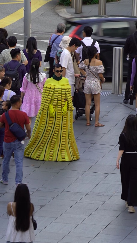 Man in a Scotch-brite sponge dress and woman with a Post-it note bag turn heads in Singapore, part of Lazada's bold campaign redefining fashion as everyday essentials.