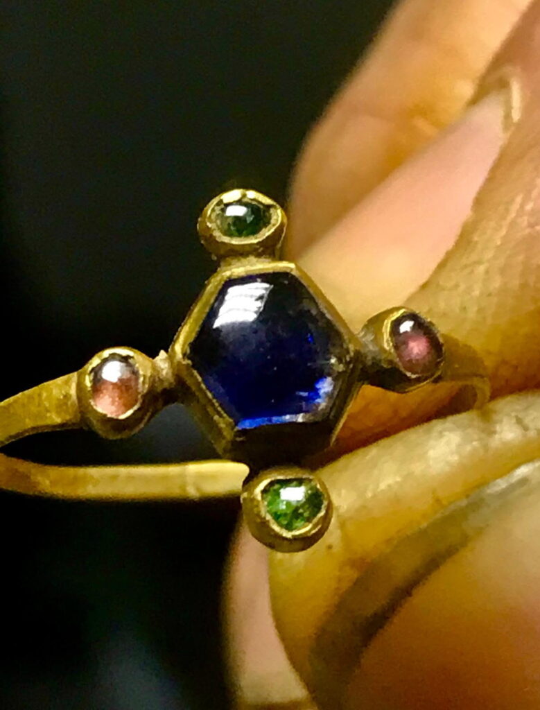 A medieval bishop's gold ring, found by metal detectorist Mark Sell in Norfolk, is expected to sell for £18,000 after being preserved for 800 years with its gemstones intact.