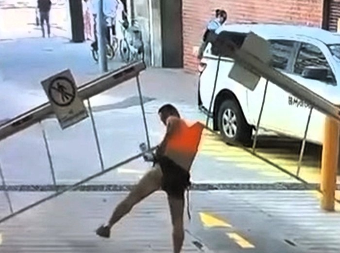 A man’s attempt to crawl under a car park barrier backfired spectacularly when it lifted - hoisting him into the air and ripping off his shirt in a viral CCTV mishap.