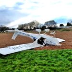 Two people survived with minor injuries after a light aircraft flipped on landing at Westonzoyland Airfield, Somerset, prompting an air safety investigation.