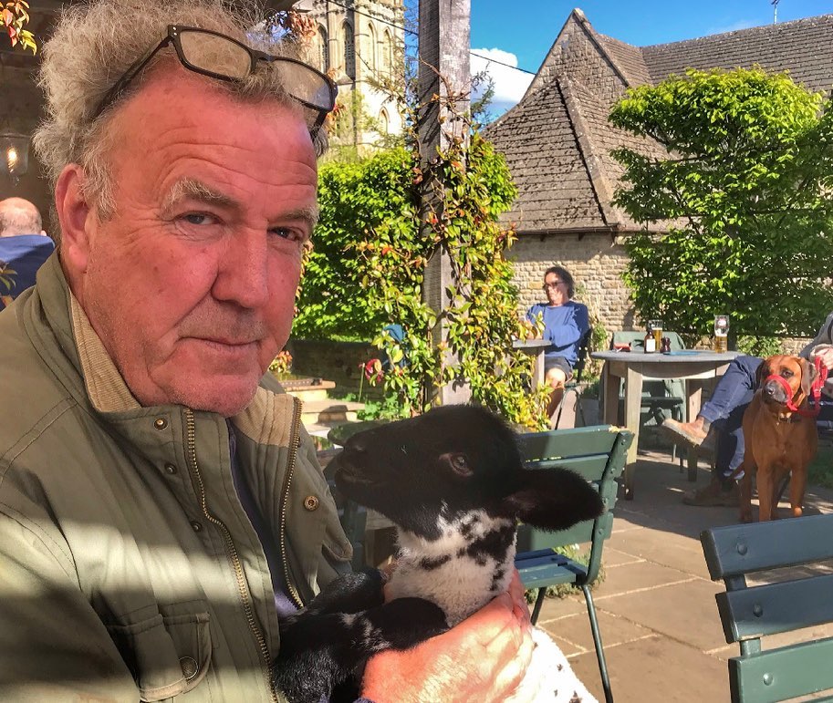 Jeremy Clarkson is facing backlash for charging £7.50 for a bacon roll and £14 for a burger without chips at his country pub, with critics calling the prices greedy.