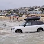 Tourists were warned after a Mini was nearly swept out to sea by a spring tide in Cornwall - locals mocked the beach parking fail as a yearly holiday tradition.