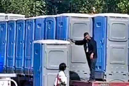 A woman was accidentally driven miles in a portable toilet after it was loaded onto a lorry in China - she emerged safely after being offloaded by a forklift.