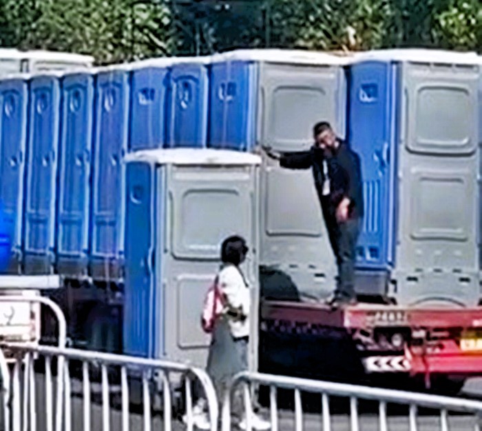 A woman was accidentally driven miles in a portable toilet after it was loaded onto a lorry in China - she emerged safely after being offloaded by a forklift.