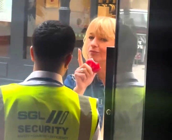 Radio DJ Sara Cox was hilariously delayed entry to a Soho bar for eating an apple - her co-host filmed the moment as the bouncer made her finish it before letting her in.