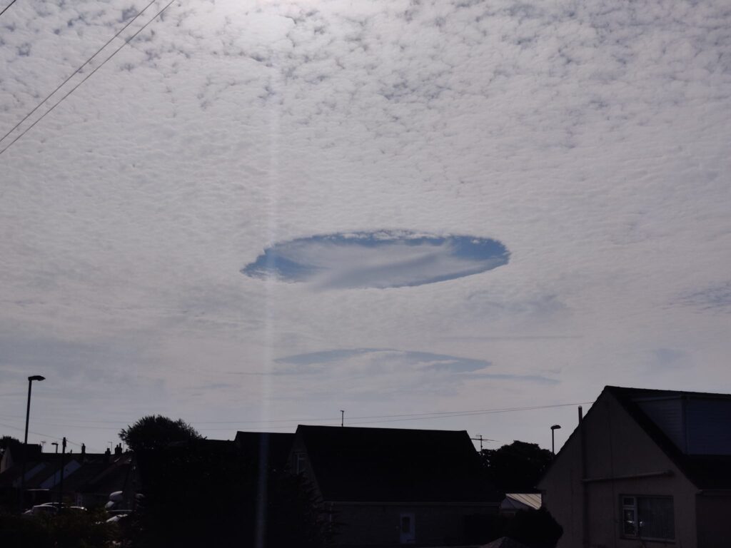 Giant UFO shaped hole appears in sky over Dorset - rare Fallstreak cloud formation stuns locals as trainee paraglider captures the eerie weather phenomenon.