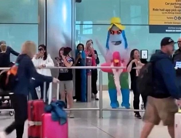 Inflatable shark in sunglasses and rubber ring greets holidaymaker at Heathrow Airport - hilarious reunion stunt leaves passengers in stitches at arrivals hall.