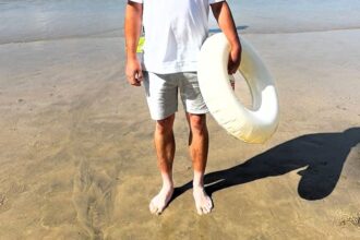 A tourist’s hilarious tanning fail left beachgoers in stitches after he revealed bright white feet against his bronzed legs in Newquay, Cornwall, with photos going viral online.