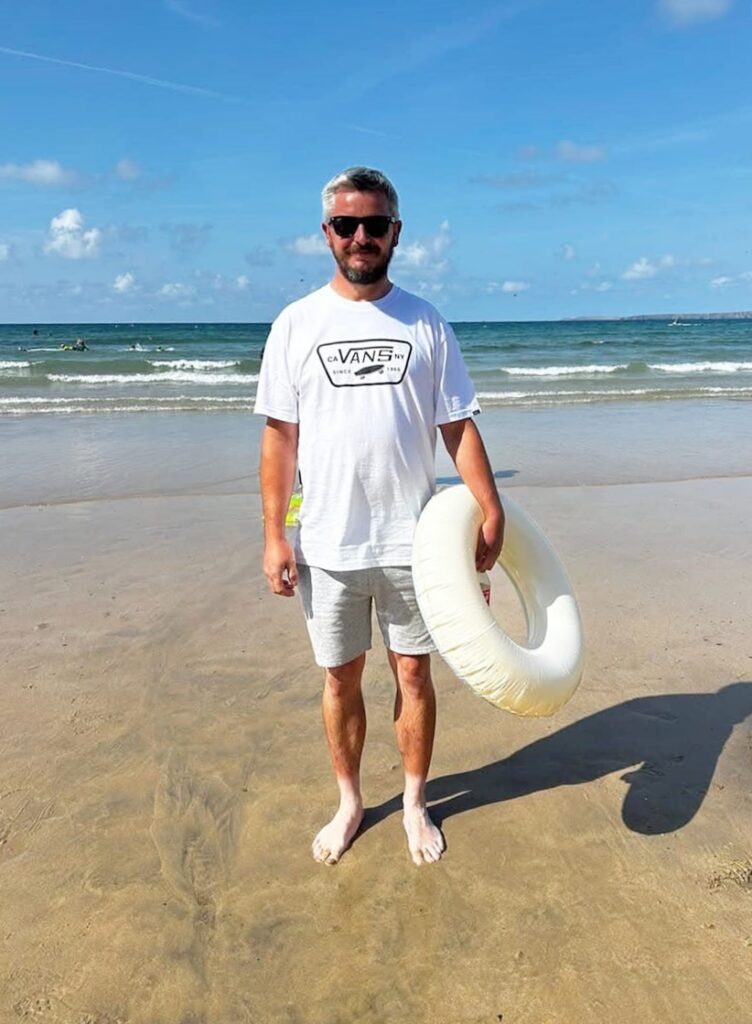 A tourist’s hilarious tanning fail left beachgoers in stitches after he revealed bright white feet against his bronzed legs in Newquay, Cornwall, with photos going viral online.