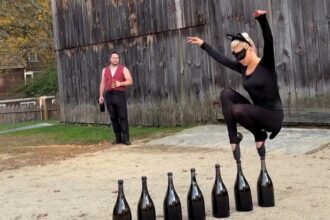 Ballerina balances on pointed toes across seven CHAMPAGNE BOTTLES while dressed as a cat (2)