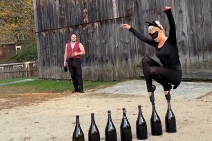 Ballerina balances on pointed toes across seven CHAMPAGNE BOTTLES while dressed as a cat (2)
