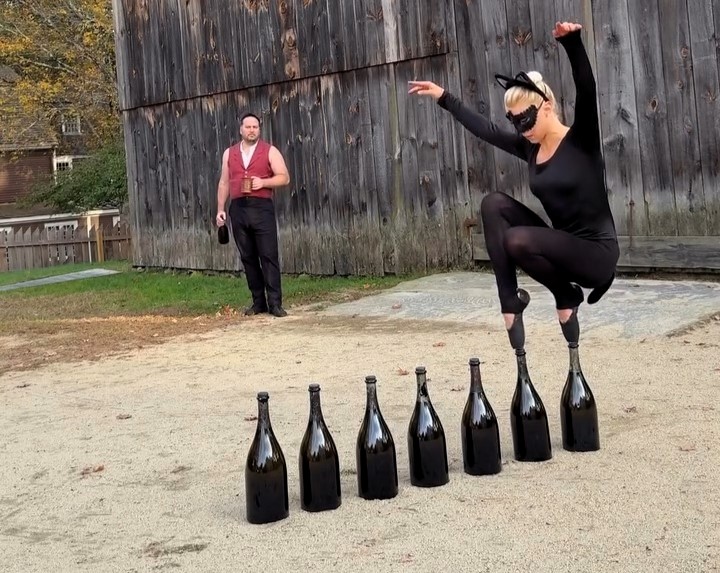 Ballerina balances on pointed toes across seven CHAMPAGNE BOTTLES while dressed as a cat (2)