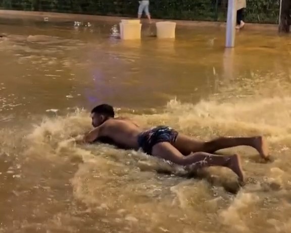 A TikToker went viral in Ibiza after belly flopping into a flooded street and pretending to swim as heavy rain left roads waterlogged and crews battled to clear the damage.