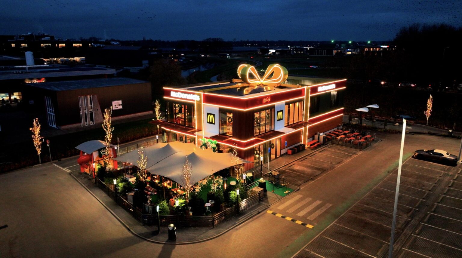 Dutch McDonald’s in Vriezenveen transforms into a giant Christmas present with a glowing bow offering festive giveaways sustainable design features and a celebratory opening for locals.