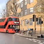 Double decker bus smashes into a bus lane sign in Docklands during rush hour leaving the front badly damaged as onlookers joke and a tow truck clears the road.