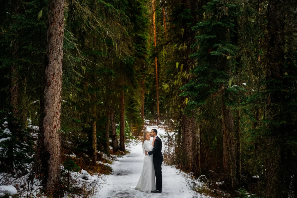 Couple braves a snowstorm to elope at Peyto Lake in Banff hiking in formalwear to say I do as stunning photos capture their windswept mountain wedding despite harsh conditions.