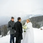 Couple braves a snowstorm to elope at Peyto Lake in Banff hiking in formalwear to say I do as stunning photos capture their windswept mountain wedding despite harsh conditions.