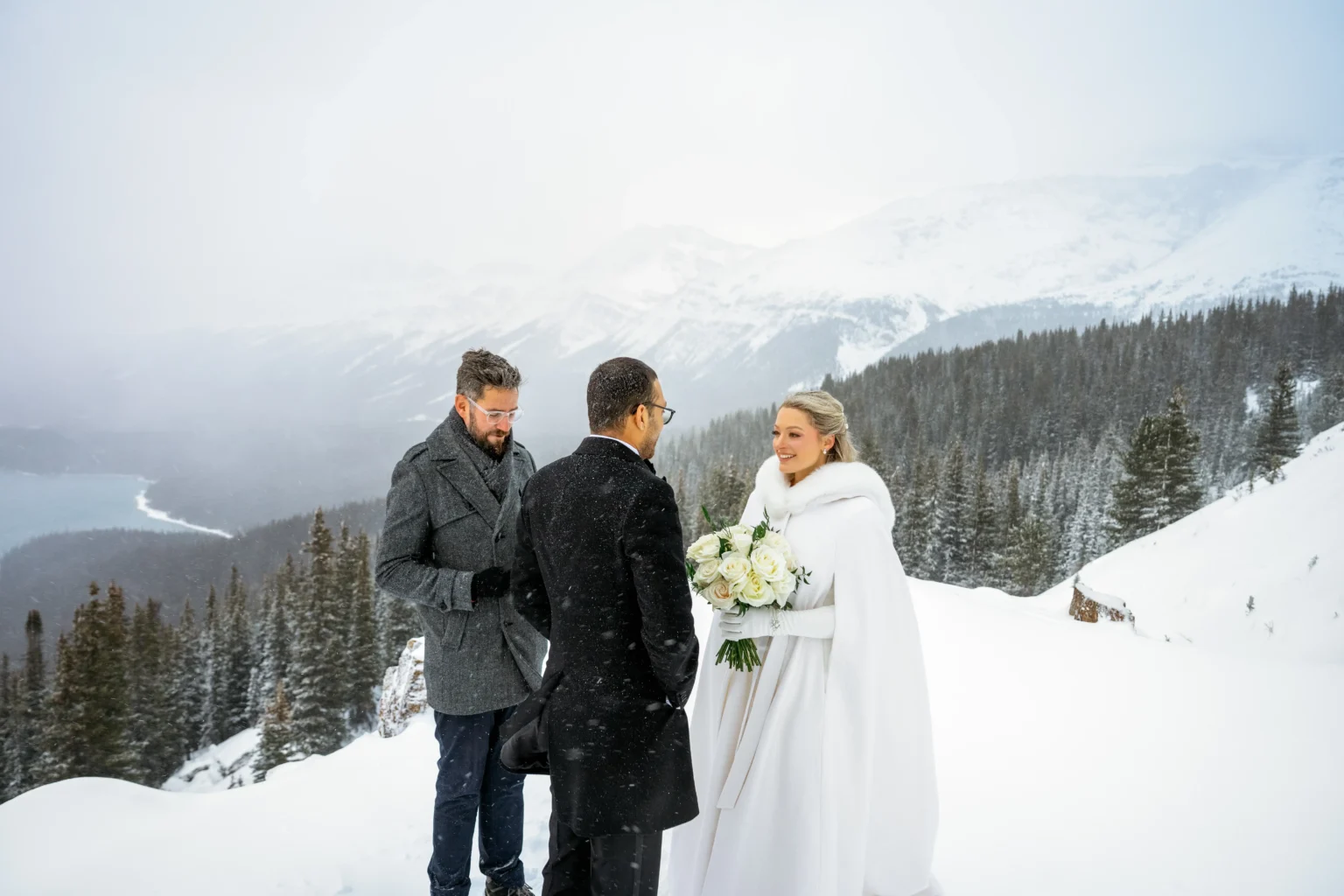 Couple braves a snowstorm to elope at Peyto Lake in Banff hiking in formalwear to say I do as stunning photos capture their windswept mountain wedding despite harsh conditions.