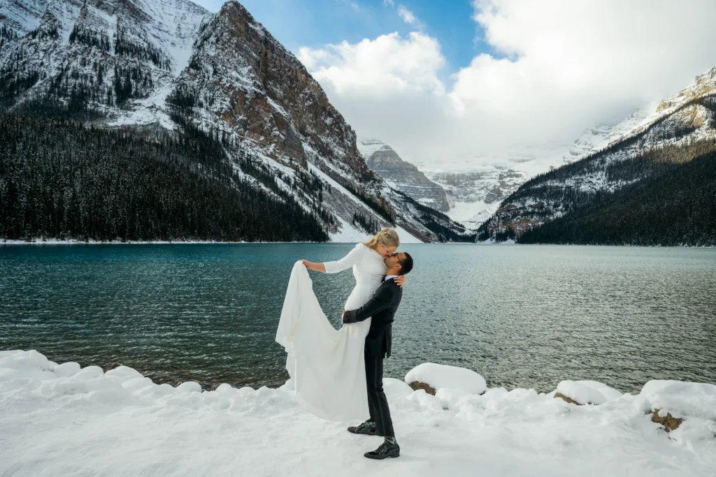 Couple braves a snowstorm to elope at Peyto Lake in Banff hiking in formalwear to say I do as stunning photos capture their windswept mountain wedding despite harsh conditions.