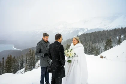 Couple braves a snowstorm to elope at Peyto Lake in Banff hiking in formalwear to say I do as stunning photos capture their windswept mountain wedding despite harsh conditions.