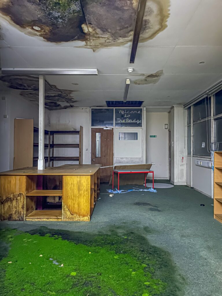 Urban explorer uncovers eerie abandoned primary school frozen in time since 2012, with ivy filled classrooms mouldy halls and grass growing indoors near Kent in darkness.