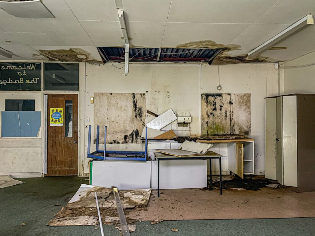 Urban explorer uncovers eerie abandoned primary school frozen in time since 2012, with ivy filled classrooms mouldy halls and grass growing indoors near Kent in darkness.