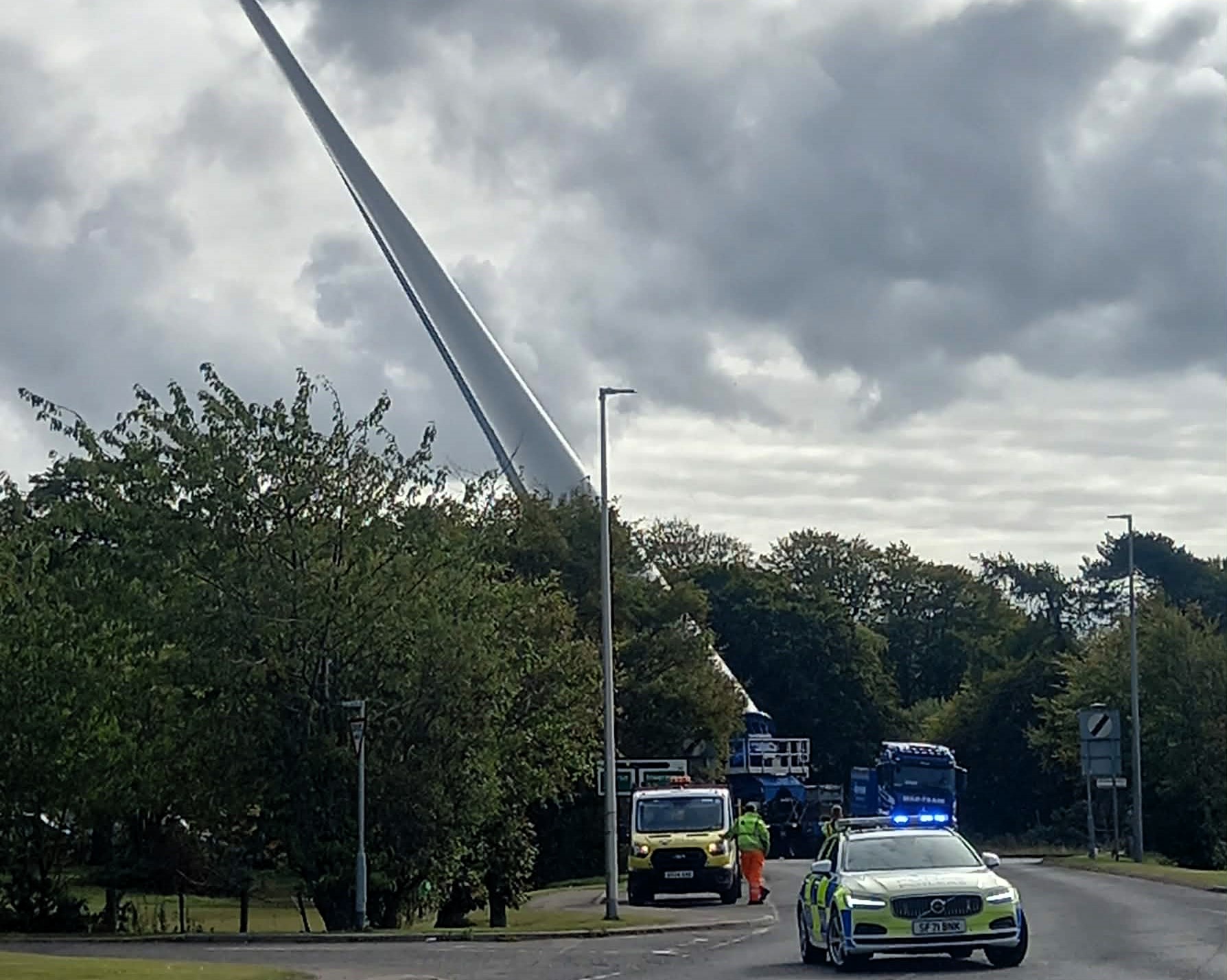 A towering 100 foot wind turbine blade amazes locals as it travels upright on a lorry through the Scottish Highlands showcasing the scale and spectacle of modern green energy projects.