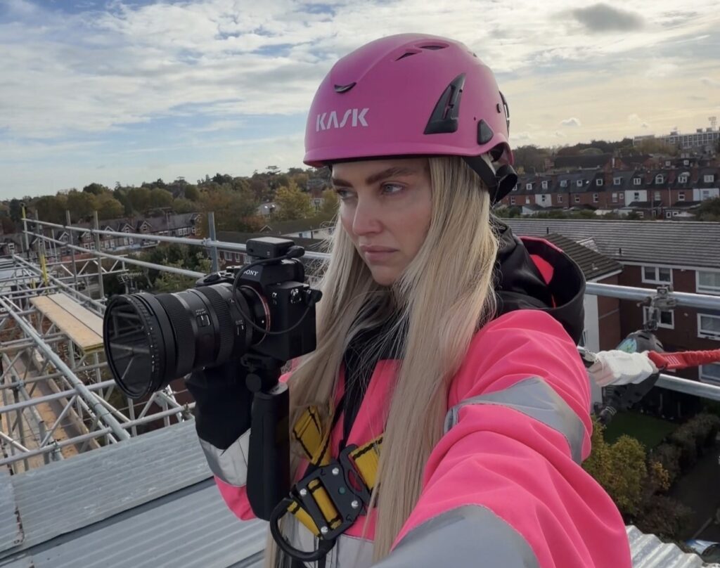 Pink hard hat videographer Abbey Moring defies critics filming scaffolding sites at height turning a mans world into viral marketing success for her boyfriends business .