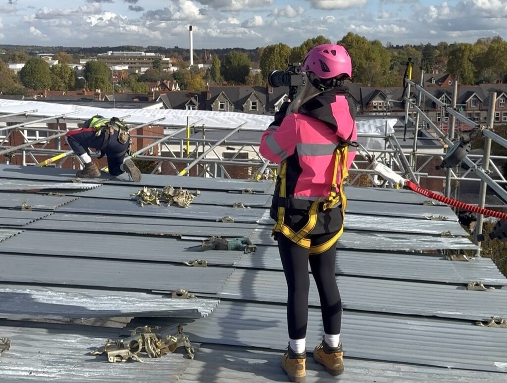 Pink hard hat videographer Abbey Moring defies critics filming scaffolding sites at height turning a mans world into viral marketing success for her boyfriends business .