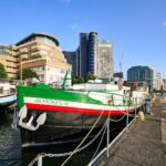 Floating hotel barge on Thames hits market for £1m. 1926 Dutch vessel with three bedrooms, panoramic river views and rare 105-year Battersea mooring lease included.