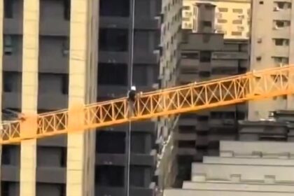 Daredevil construction worker filmed walking along crane boom at 10-storey height without safety harness in Taoyuan, Taiwan, prompting inspection and fines up to £7,085 for safety violations.
