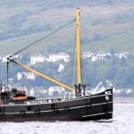 Pair of dolphins perform amazing acrobatics near heritage steamboat Vic 32 at Wemyss Bay, Firth of Clyde. Show-off marine mammals delighted onlookers near Glasgow.
