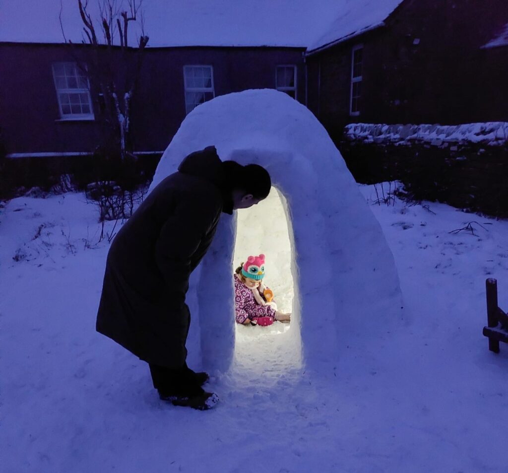 Stonemason builds igloo with working fireplace and chimney during Beast from the East - Kyle Doran hand crafts cosy shelter in Orkney garden for toasting marshmallows with daughter.
