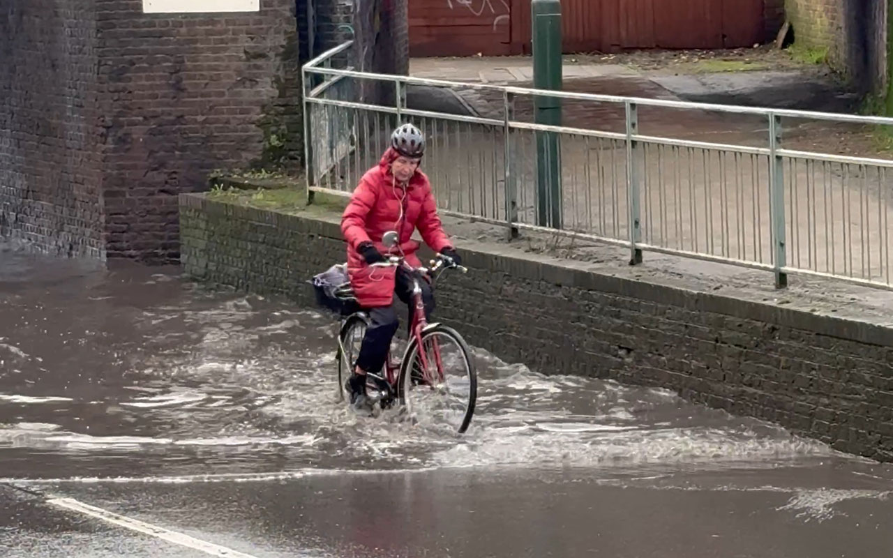 Determined cyclist rides through heavily-flooded road with dirty water ...