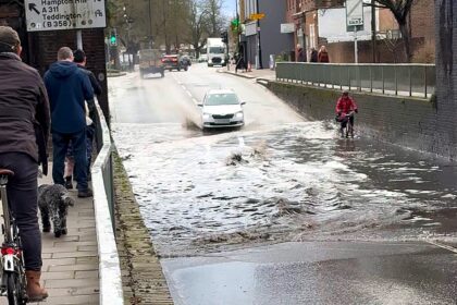 A fearless cyclist pedalled through knee deep floodwater on Heath Road in Twickenham, unfazed even as a passing car sent waves crashing over her under a bridge