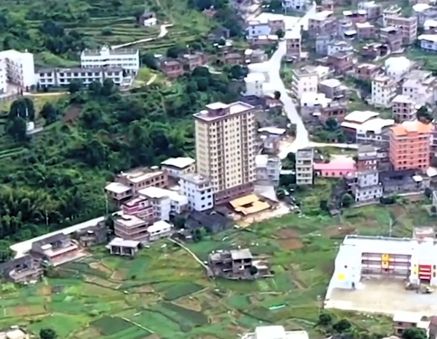 Zhou family built 15-storey skyscraper in rural China to house over 100 relatives across four generations. The decade-old tower has 22 apartments and sticks out from village.