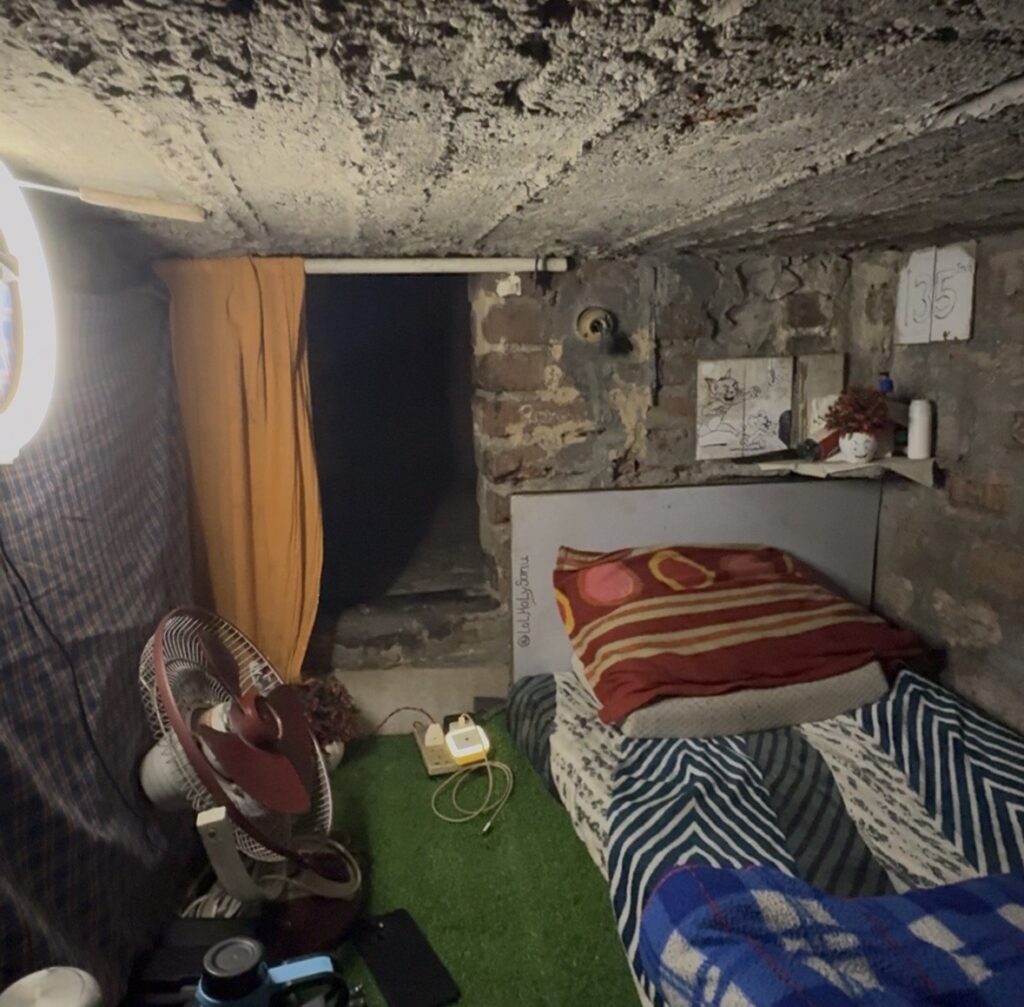 A man living in a tiny concrete box with no windows and a ceiling so low he can't stand up pays just £40 a month in rent - and turned his cramped space into a viral influencer career.