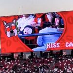 Couple caught on kiss cam at Mexican soccer match desperately hide faces as crowd jeers. Man turns 180 degrees away. Viral moment compared to Coldplay cheating scandal.