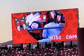 Couple caught on kiss cam at Mexican soccer match desperately hide faces as crowd jeers. Man turns 180 degrees away. Viral moment compared to Coldplay cheating scandal.